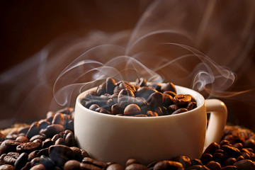 White cup and coffee beans on dark background, close up view
