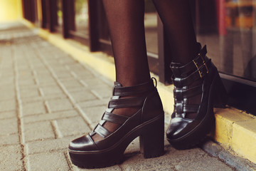 Elegant outfit. Closeup of stylish black leather shoes. Fashionable girl posing on street of the old city. Female fashion concept. Copy space for text. Toned