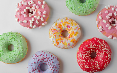 Tasty donuts with colorful sprinkles on light background