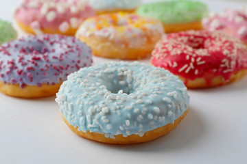 Tasty donuts with colorful sprinkles on light background