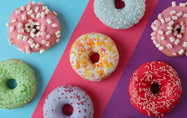 Tasty donuts with sprinkles on colorful background
