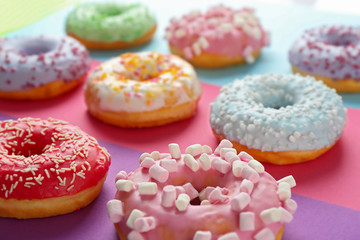 Tasty donuts with sprinkles on colorful background