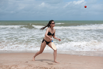 Beautiful young brunette playing beach tennis in Brazil