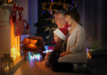 Little girl and her grandparents near fireplace decorated for Christmas