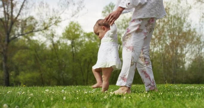 in a sunny summer day A newborn takes its first steps running toward the smiling mother happy and spensierata.I first steps that you never forget in life. And mom helps her to take the first steps.
