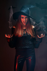 Young woman dressed in witch costume for Halloween, on dark background