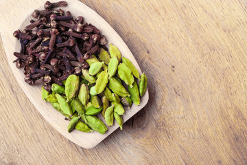 cardamom pods and cloves on wooden spoon