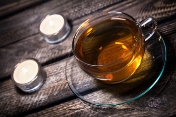 A Cup Of Tea With 2 Tealights On Old Wooden Floorboards