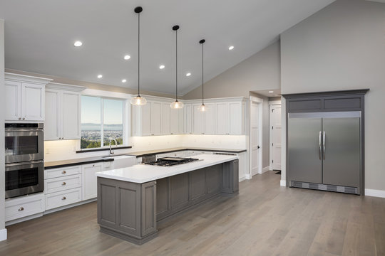 Amazing new contemporary with large white Kitchen with kitchen Island and grey counter tops.