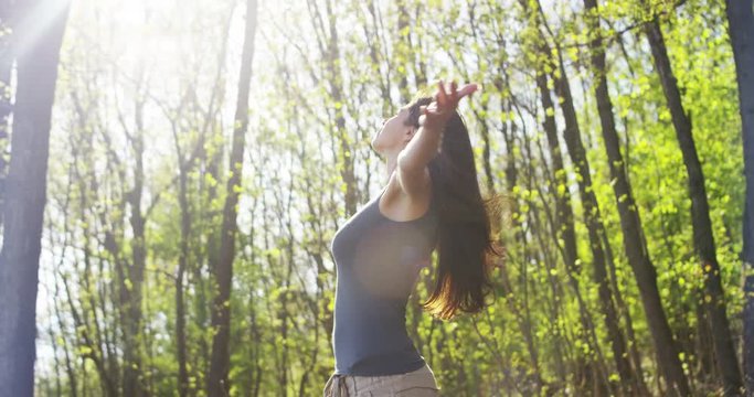 beautiful young woman admires the happy and carefree nature in a meadow at sunset in slow motion