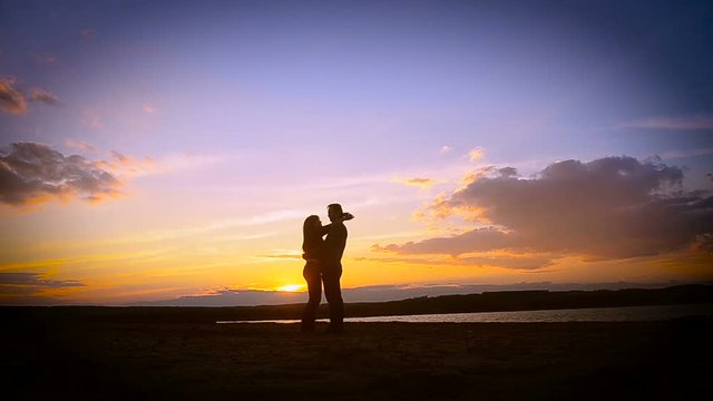 enamored guy and the girl, hugging at sunset against a blue sky on the bank of the river, lake