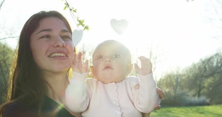 super slow motion of Mom and daughter play and are very happy under a rain of petals at sunset surrounded by nature in 4K - Powered by Adobe