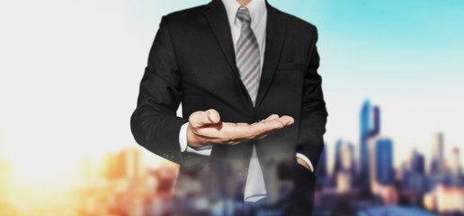 Businessman with hand in holding something position, with defocus panoramic city view in sunrise background