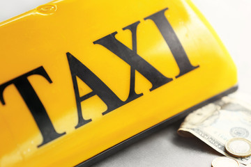 Yellow taxi roof sign with money, closeup