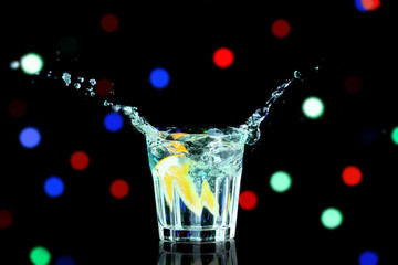 Fototapeta na wymiar Colorful cocktail with splash on blurred lights background