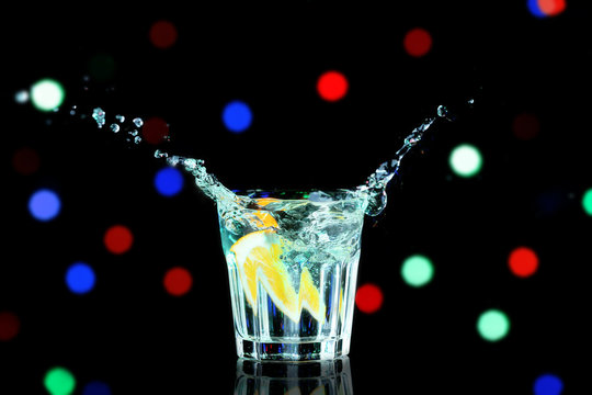 Colorful cocktail with splash on blurred lights background