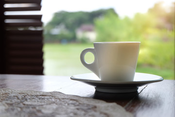 closeup white cup of coffee on wooden table with nature background