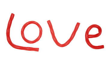 love for sweets. the inscription love is laid out from the red twisted licorice candy. isolated on a white background