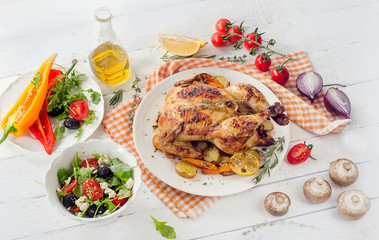 Roasted chicken with vegetables and salad on a white wooden back