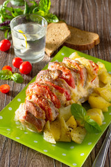 Baked meat with cheese and tomato with baked potatoes on a woode