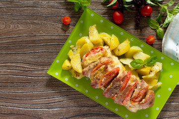 Baked meat with cheese and tomato with baked potatoes on a woode