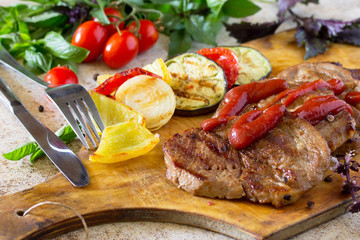 Beef steaks on the grill and grilled autumn vegetables: peppers,