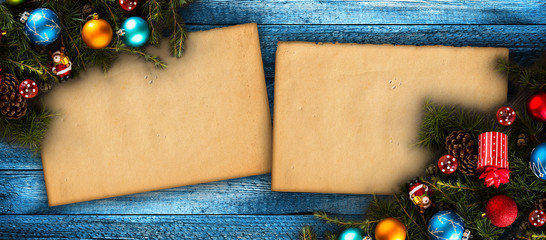 Merry Christmas Frame with real wood green pine, colorful baubles, gift boxe and other seasonal stuff over an old wooden aged background