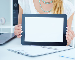 Young business woman showing blank screen of tablet in office.