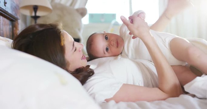  Happy Mother and Baby kissing and hugging, Resting in bed together,  Maternity concept Motherhood Beautiful Happy Family Stock Video Footage in Slow Motion