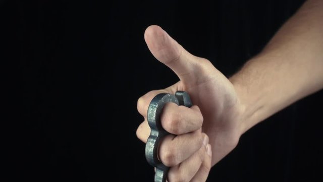 Male hand with knuckle-duster gesturing Thumbs Up