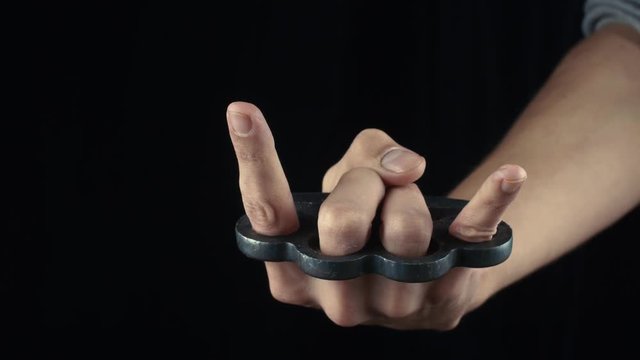 Male hand with knuckle-duster showing devil horn gesture