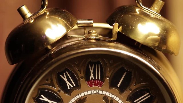 Old golden clock is ticking closeup.