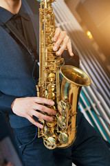 Musical instrument saxophone close-up. Hands on a musical instrument. Young guy playing jazz.