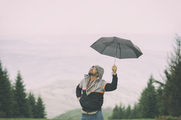 Man in nature holding umbrella.

