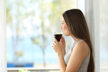 Girl drinking coffee looking through a window