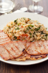 grilled meat with rice on white plate on wooden background