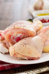 raw chicken on white plate with oil and pepper on brown wooden b