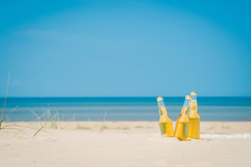 Ice cold beer bottles in the sand under the sun
