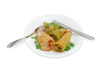 Cooked cabbage rolls, fork and knife on white dish