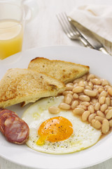 fried egg with beans, chorizo and toasts on white plate