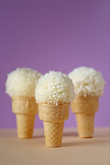 Food concept. ice cream with pompons. waffle cups with white pompoms on a purple background