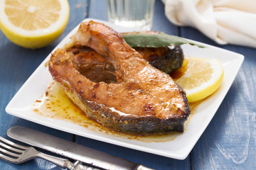 fried salmon with lemon on white dish