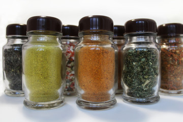 Spices in glass jars on a white background