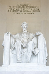 Statue of American president Abraham Lincoln seated in white marble under an epitaph at the Lincoln Memorial in Washington DC, USA 