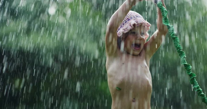 On a sunny hot day, a baby is playing with water and enjoying it very bathing with water. The baby is very happy and smiling because the water is cold.