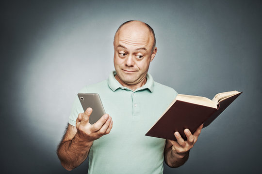 man holding a book in one hand into another smart phone