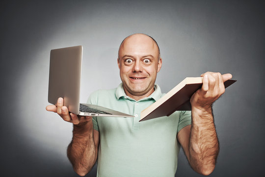 man holding a book in one hand and a laptop in the other
