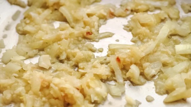 Closeup of sizzling hot onion and garlic cooking in pan as canned diced tomato is added to make pasta sauce, slow motion