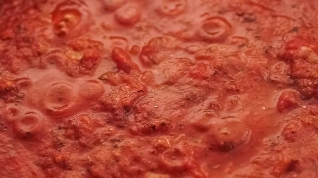Gourmet fresh sliced field mushrooms added to simmering red tomato pasta sauce and mixed with spoon, closeup slow motion