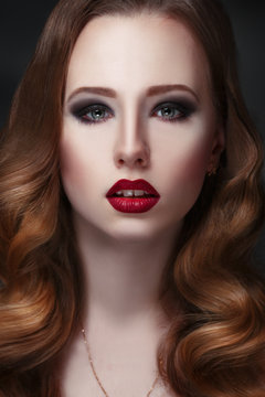 Fashion beauty portrait of gorgeous girl with curls and red lipstick in the style of Hollywood on a black background